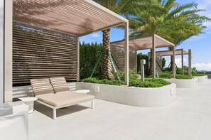 Ein moderner Außenbereich mit Liegestuhl, kleinem Tisch und einer Pergola.