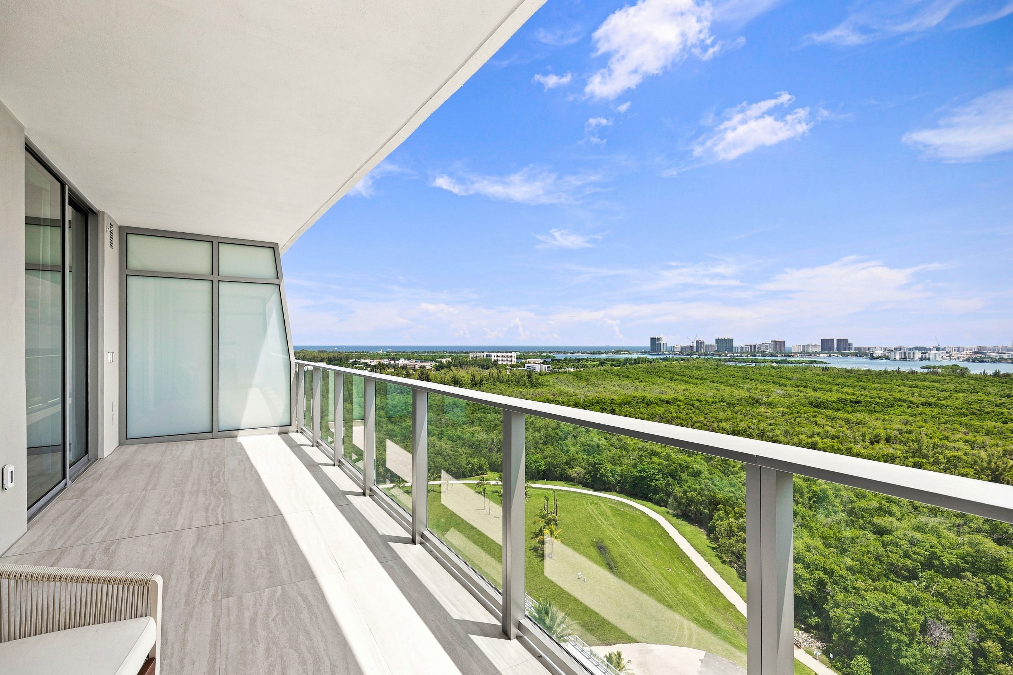 A balcony with a view of a city skyline and a green landscape.