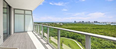 A balcony with a view of a city skyline and a green landscape.