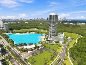 Ein Hochhaus-Hotel mit Pool, umgeben von Grünflächen und einer Stadtansicht.