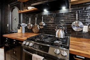 A kitchen with a stainless steel stove, hanging pots, and a wooden countertop. - Heart of Ohio City, Sleeps 8 & Fenced Yard (Cleveland)
