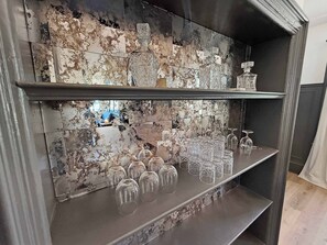 Eine Barbereich mit Marmorrückwand und Regalen für Gläser und Flaschen.