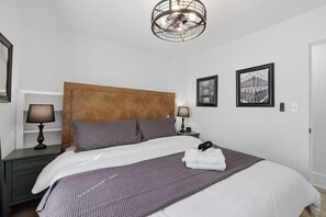A hotel room with a bed, two bedside tables, a headboard, a ceiling fan, and two framed pictures on the wall. - Heart of Ohio City, Sleeps 8 & Fenced Yard (Cleveland)