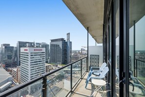 Un balcon offrant une vue sur le paysage urbain, avec des bâtiments dont on peut voir les enseignes.