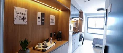 Una cocina moderna con muebles de madera, una encimera con cafetera y una planta en maceta.