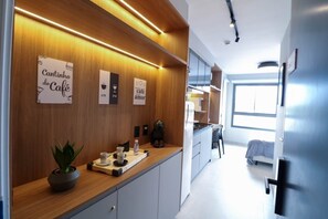 A modern kitchen with wooden cabinetry, a countertop with a coffee maker, and a potted plant. - Lindo apto ao lado do Aerop de Congonhas (São Paulo)