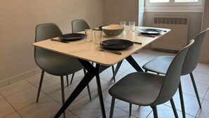 A dining area with a table set for four, including plates, glasses, and cutlery. - Apartment in Downtown Montluel (Montluel)