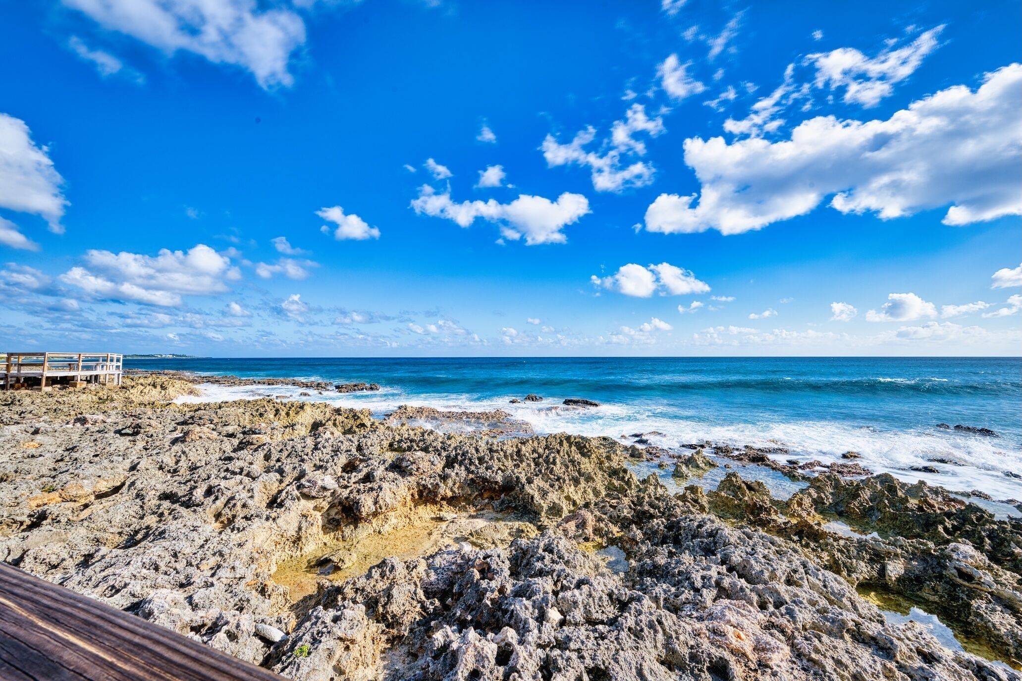 A rocky beach with a wooden walkway leading to a structure.