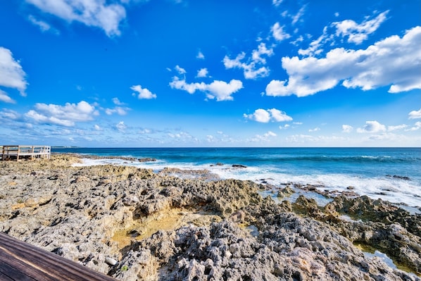A rocky beach with a wooden walkway leading to a structure.