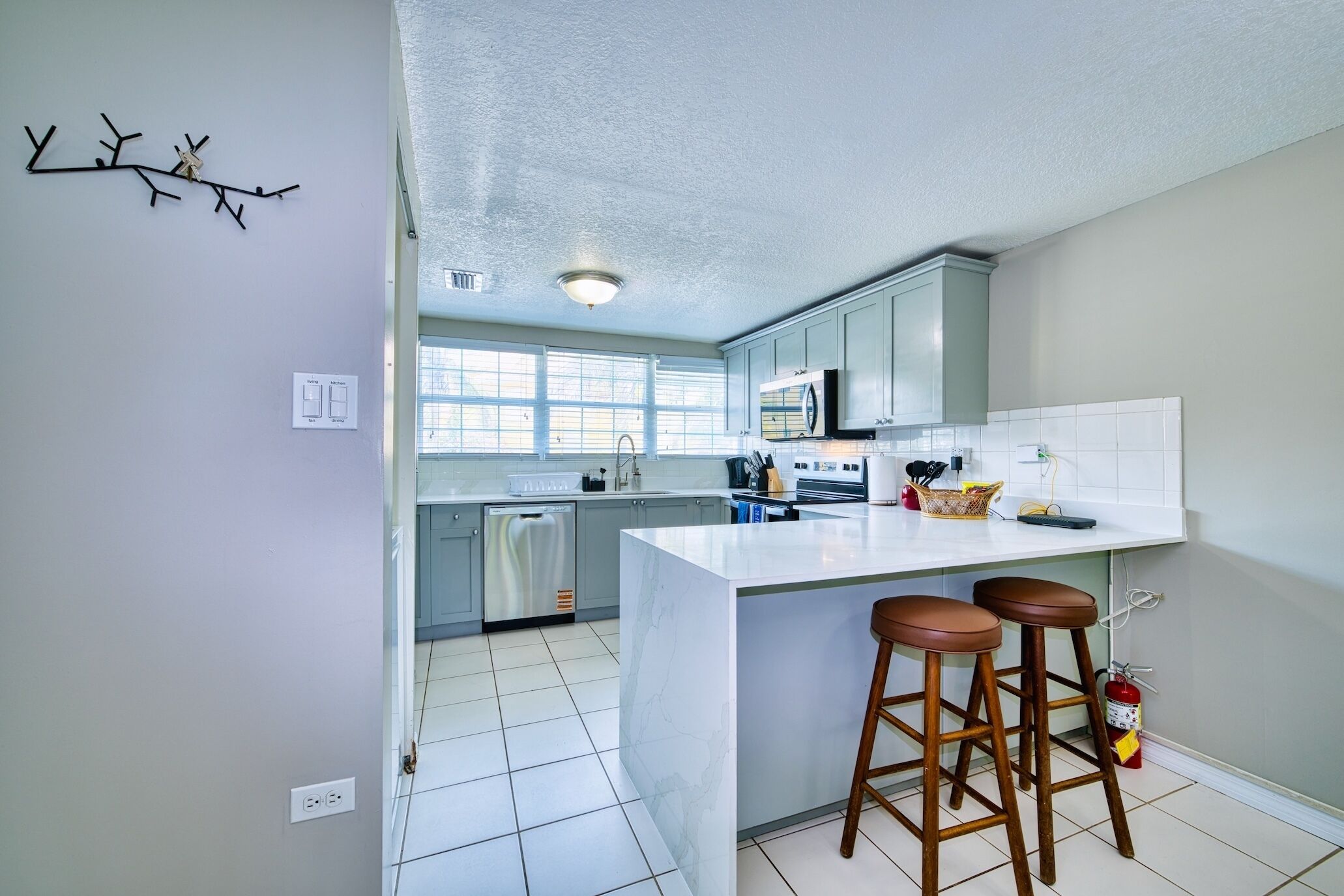 Una cocina moderna con una isla central, taburetes de bar y vista al área de comedor.
