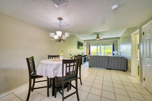 A dining area with a round table, chairs, and a ceiling fan.