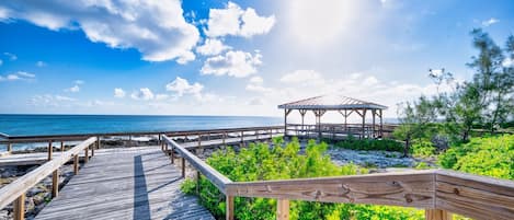 A wooden boardwalk leading to a gazebo by the beach.