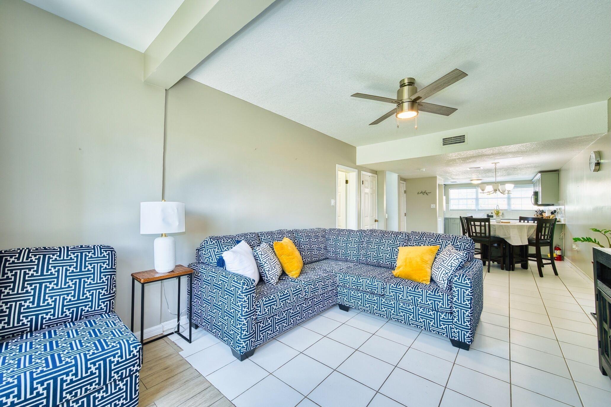 A living room with a sectional sofa, a side table, and a ceiling fan.