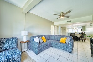 A living room with a sectional sofa, a side table, and a ceiling fan.