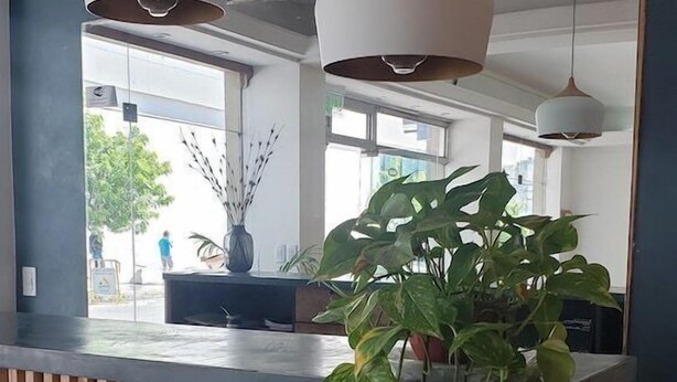 Un área de recepción con mostrador de madera, dos lámparas colgantes y un espejo grande.