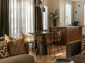 A living room with a sofa, a dining table with chairs, a coffee machine, and a cabinet. - 11 Earl by MajorDomo | Modern 2-Bedroom Apartment in the Heart of Downtown Queenstown, Steps to Lake, Dining & Shops (Queenstown)