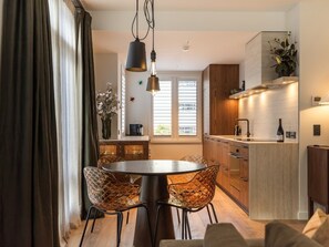 A modern kitchen with a central island, wooden cabinets, and a built-in oven. - 11 Earl by MajorDomo | Modern 2-Bedroom Apartment in the Heart of Downtown Queenstown, Steps to Lake, Dining & Shops (Queenstown)