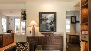 A living room with a sofa, a lamp, a television, and a wooden cabinet. - 11 Earl by MajorDomo | Modern 2-Bedroom Apartment in the Heart of Downtown Queenstown, Steps to Lake, Dining & Shops (Queenstown)