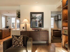A living room with a sofa, a lamp, a television, and a wooden cabinet. - 11 Earl by MajorDomo | Modern 2-Bedroom Apartment in the Heart of Downtown Queenstown, Steps to Lake, Dining & Shops (Queenstown)