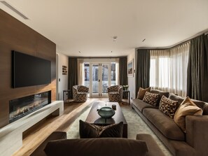 A modern living room with a fireplace, a flat-screen TV, a sofa, and two armchairs. - 11 Earl by MajorDomo | Modern 2-Bedroom Apartment in the Heart of Downtown Queenstown, Steps to Lake, Dining & Shops (Queenstown)