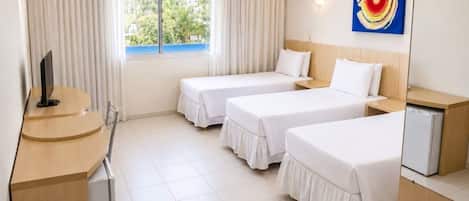 Quarto de hotel com duas camas, uma mesa, uma televisão e uma janela com cortinas.