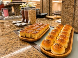 Una mesa de buffet con diversos alimentos, incluyendo bollos y una bandeja de productos horneados.