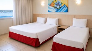 Una habitación de hotel con dos camas, un cuadro en la pared y una ventana con cortinas.
