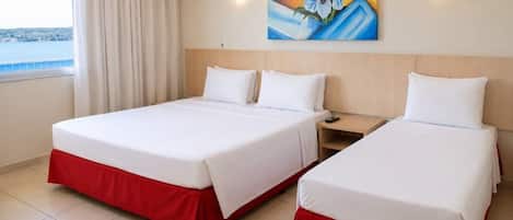 Una habitación de hotel con dos camas, un cuadro en la pared y una ventana con cortinas.