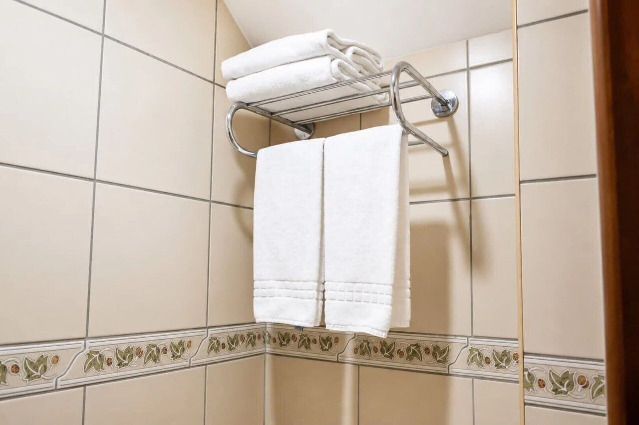 Un baño con un perchero que sostiene dos toallas dobladas.