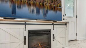 A fireplace with a glass door, a wooden mantel, and a view of a lake through the window above. - East Austin Home for 4 w/ BBQ Grill, Near DT! (Austin)