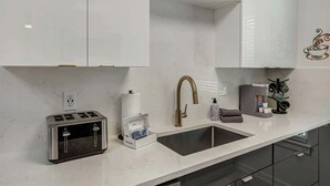 A modern kitchen with a built-in toaster, a stainless steel sink, and a coffee machine. - East Austin Home for 4 w/ BBQ Grill, Near DT! (Austin)