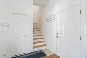 A hallway with white doors, a staircase, and a rug. - Blue Mountain View | Private Pool, Rooftop Deck & Bikes (Santa Rosa Beach)
