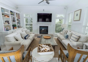 A living room with a fireplace, white sofas, a coffee table, and a TV. - Blue Mountain View | Private Pool, Rooftop Deck & Bikes (Santa Rosa Beach)