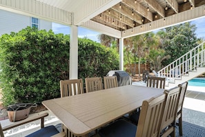 An outdoor patio with a table and chairs, surrounded by greenery and a pool. - Blue Mountain View | Private Pool, Rooftop Deck & Bikes (Santa Rosa Beach)