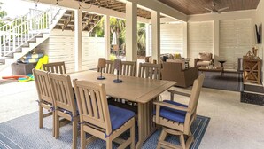 An outdoor covered patio with a wooden table and chairs, a ceiling fan, and a view of the outside. - Blue Mountain View | Private Pool, Rooftop Deck & Bikes (Santa Rosa Beach)
