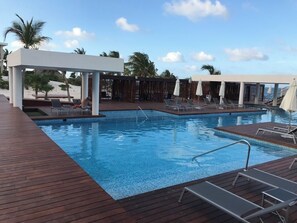 A pool area with lounge chairs and umbrellas, surrounded by wooden decking and palm trees. - THE CROWN JEWEL: The largest, private property with direct beach access (ISLA MUJERES SONA PENINSULAR)