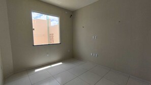 A room with a large window, tiled floor, and light-colored walls.