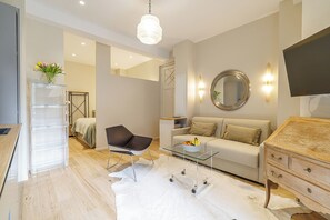 Ein modernes Wohnzimmer mit einem Glastisch, einer Couch, einem Sessel und einem Holzschrank.
