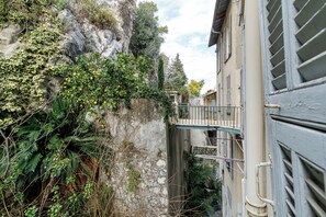 A narrow alleyway with a stone wall on one side and a building with a balcony on the other. - Roch - NEW renovated 1BR w balcony - Castle Hill (Nice)