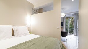Et soveværelse med en seng, et natbord, en lampe og udsigt til en balkon med udendørs møbler.