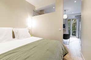 A bedroom with a bed, a nightstand, a lamp, and a view of a balcony with outdoor furniture. - Roch - NEW renovated 1BR w balcony - Castle Hill (Nice)