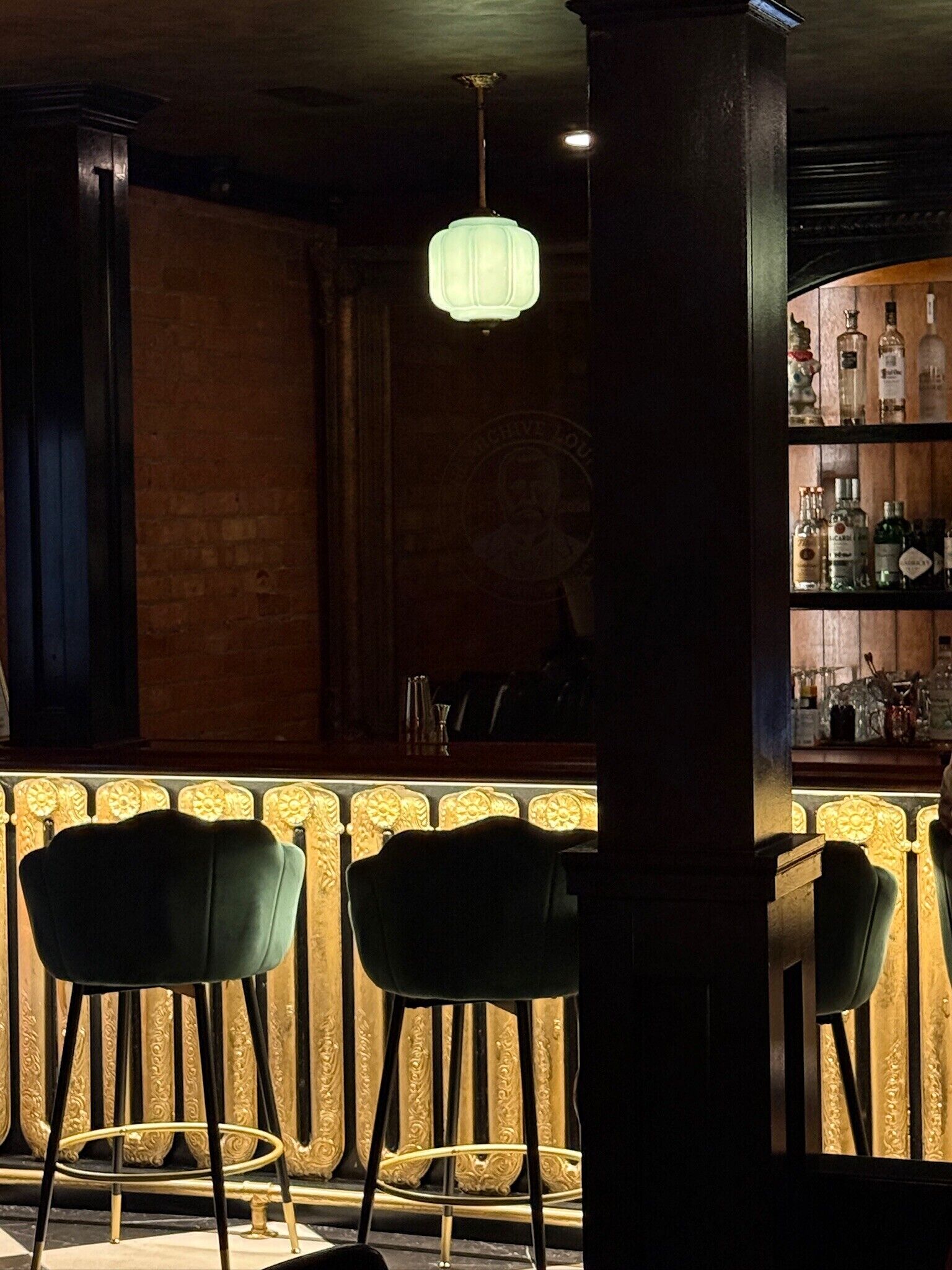 Un espace bar comprenant un comptoir, des tabourets de bar et une variété de bouteilles.