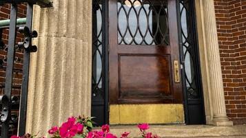 A public library entrance with a dark wooden door, a decorative metal gate, and a column.
