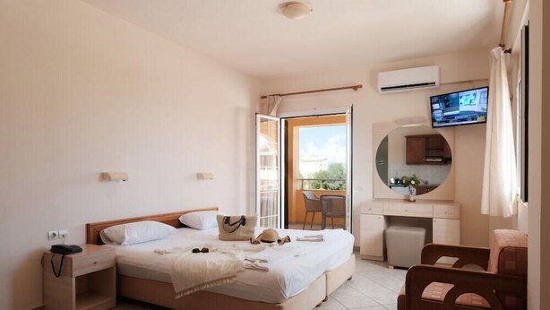 Ein Hotelzimmer mit Bett, Nachttisch, Fernseher und Blick ins Freie.