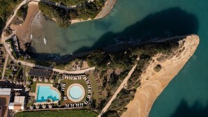 Luftaufnahme eines Küsteneigentums mit Schwimmbad, Strand und einer Brücke.