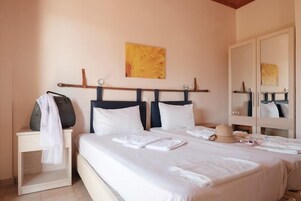 Una habitación de hotel con cama, mesitas de noche, un espejo y un cuadro en la pared.