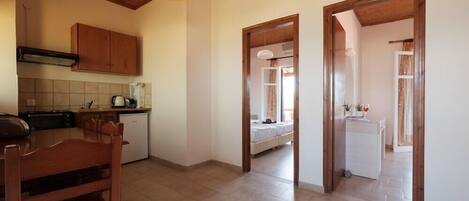 A kitchen with wooden cabinets, a dining table, and a ceiling light. There are two doorways leading to other rooms.