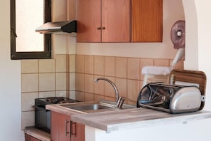 A kitchen with a stove, sink, and a toaster on the countertop. - Canal D Amour Apartments (Corfu)