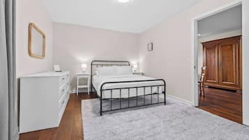 A bedroom with a bed, bedside tables, a dresser, a mirror, and a wardrobe.