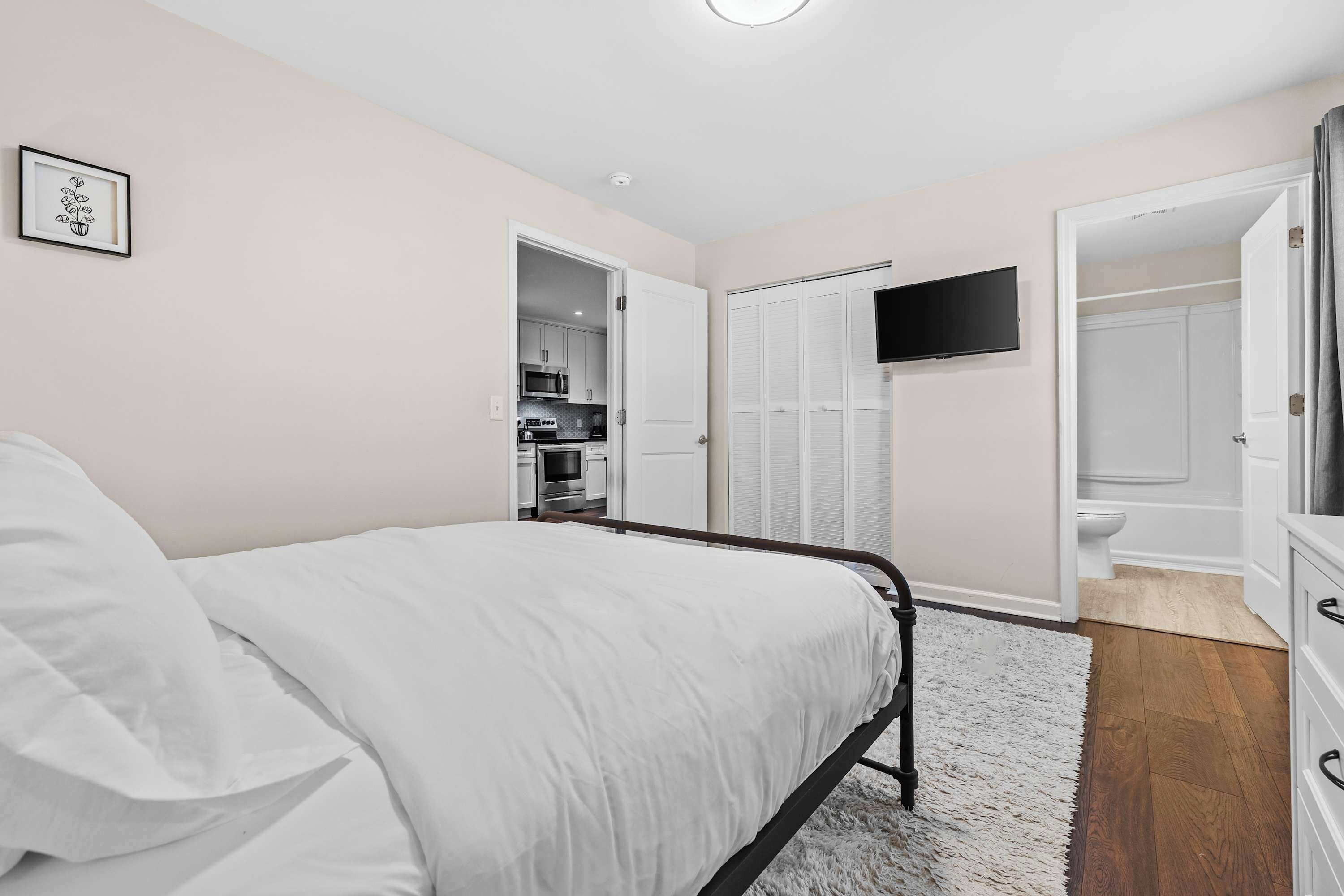 Un dormitorio con una cama, un televisor montado en la pared y un armario con puerta corredera.
